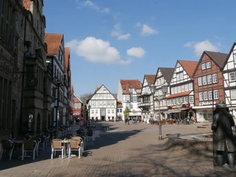 Historischer Marktplatz in Rinteln mit Fachwerkhäusern, gepflasterter Fläche und einer Brunnenfigur.