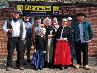 Fehntheater trifft ostfriesische Teekultur Ensemble des Fehntheaters in historischen Kostümen vor Backsteinfassade.