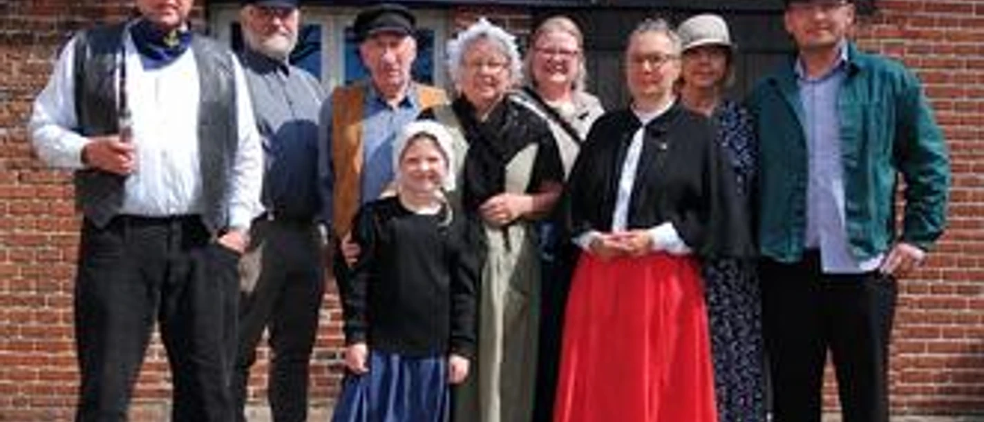 Fehntheater trifft ostfriesische Teekultur Ensemble des Fehntheaters in historischen Kostümen vor Backsteinfassade.