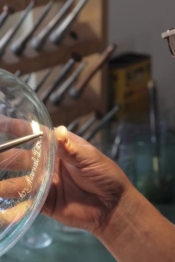 Glashütte Gernheim: Glasbe- und Verarbeitung Glasbläser bearbeitet mit Präzision ein heißes Glasobjekt, umgeben von Werkzeugen in der Werkstatt.