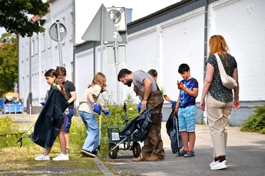 Rettungsdienst für Relikte Rodenbeck Das Bild zeigt Kinder und Erwachsene die Gegenstände von der Straße in einem Plastiksack stecken.