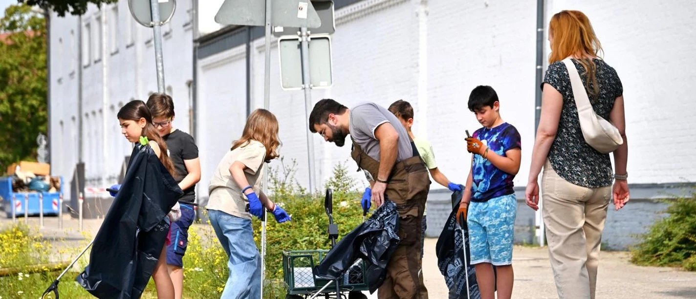 Rettungsdienst für Relikte Rodenbeck Das Bild zeigt Kinder und Erwachsene die Gegenstände von der Straße in einem Plastiksack stecken.