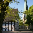 Café zur Linde und die Kirche St. Lambertus Langenberg Fachwerkhaus „Café zur Linde“ neben der steilen Kirchturmspitze der St. Lambertus-Kirche, umrahmt von Bäumen.