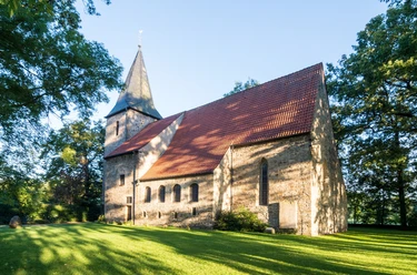Alte St. Alexander Kirche Kirche mit rotem Ziegeldach, spitzem Turm, umgeben von Bäumen und gepflegtem Rasen.