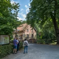 Knollmeyers Mühle Old brick mill surrounded by trees with three walkers on the country road.