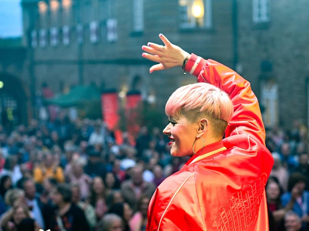 Broicher Schlossparty, Mülheim an der Ruhr Sängerin in roter Jacke winkt dem Publikum bei einem Open-Air-Konzert zu