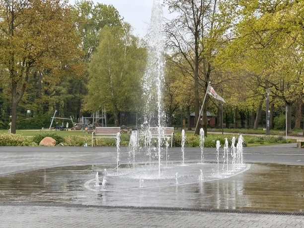 Wasserspiel im Herbst Sprudelndes Wasserspiel an den Strandterrassen Steinhude vor grünen Bäumen und Bänken.