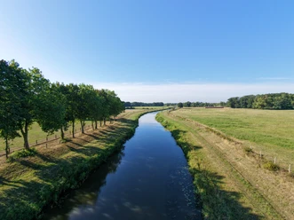 Große Aue von oben (1).jpg Große Aue schlängelt sich zwischen Wiesen, Feldern und Baumreihen unter blauem Himmel.