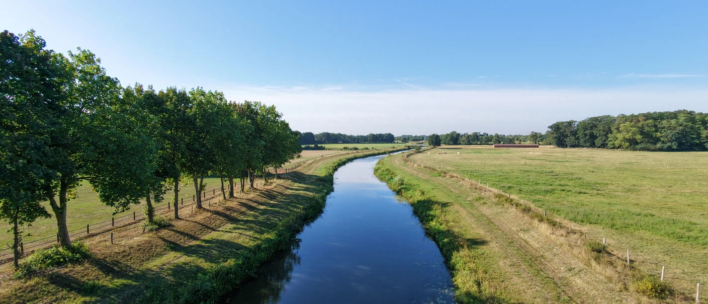Große Aue von oben (1).jpg Große Aue schlängelt sich zwischen Wiesen, Feldern und Baumreihen unter blauem Himmel.