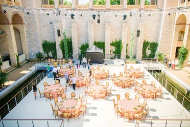 BALZER & Co. GmbH_Event Catering_Outdoor Area of an Event Venue The outdoor area of an event venue with set round tables, chairs, a stage, and event equipment. Several people are setting up the space for a catering event or other gathering.