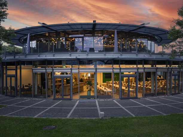 GenoHotel_Außenaufnahme In der Abenddämmerung ist die Glasfassade vom GenoHotel sichtbar.