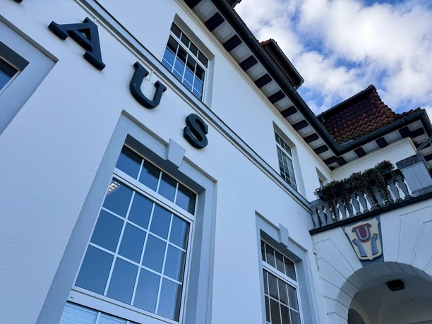 Rathaus Uchte (1).jpeg Fassade des Rathauses Uchte mit großen Fenstern, Schriftzug und Wappen am Eingang.