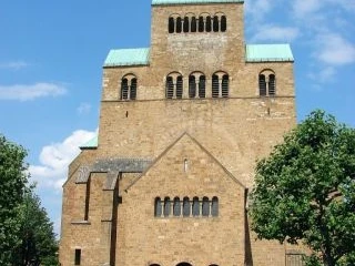 Historische Ansicht des Mindener Doms mit markantem Turm und Bäumen im Vordergrund.