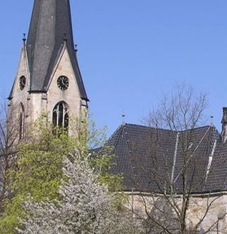 Kirche Kleinenbremen Die evangelische Kirche Kleinenbremen vor blauem Himmel, umgeben von blühenden Bäumen im Frühjahr.