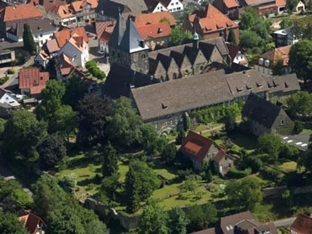 Luftaufnahme Obernkirchen Luftaufnahme von Obernkirchen mit der Stiftskirche, umgeben von dicht bebauten roten Dächern und Bäumen.