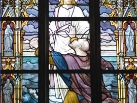Fenster Obernkirchen Buntes Kirchenfenster mit Jesus im weißen Gewand, umgeben von Meereswellen und blauem Himmel.