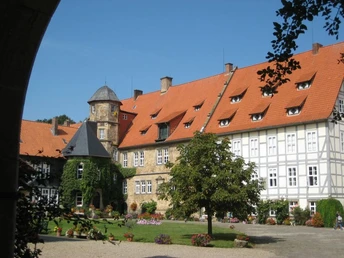 Schloss von Münchhausen Historisches Schloss Münchhausen mit rotem Dach, umgeben von gepflegten Gärten und Bäumen.