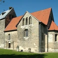 Sigwardskirche Romanische Kirche aus Naturstein mit rotem Ziegeldach, umgeben von Grünfläche und Bäumen.