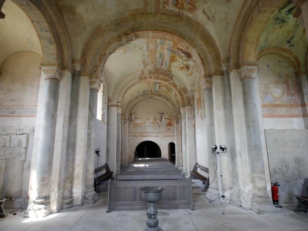 Sigwardskirche von innen Innenraum der Sigwardskirche mit bemalten Gewölben, steinernen Säulen und einem schlichten Taufbecken.