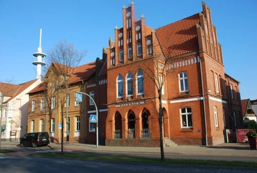 Rathaus Stolzenau Backsteingebäude mit gotischen Fenstern, das Stolzenauer Rathaus; Funkmast im Hintergrund.