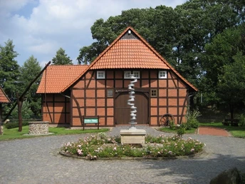 Heringsfängermuseum Heimsen Fachwerkhaus des Heringsfängermuseums Heimsen mit Wald im Hintergrund und Blumengarten im Vordergrund.