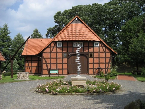 Heringsfängermuseum Heimsen Fachwerkhaus des Heringsfängermuseums Heimsen mit Wald im Hintergrund und Blumengarten im Vordergrund.