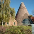 Glashütte Gernheim Historische Glashütte Gernheim mit auffälligem Kegeldach aus Backstein, umgeben von Bäumen.