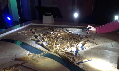 Auf dem Bild ist ein Stadtmodell zu sehen, das sich im Dunkeln befindet und nur mit einer Taschenlampe angeleuchtet wird.