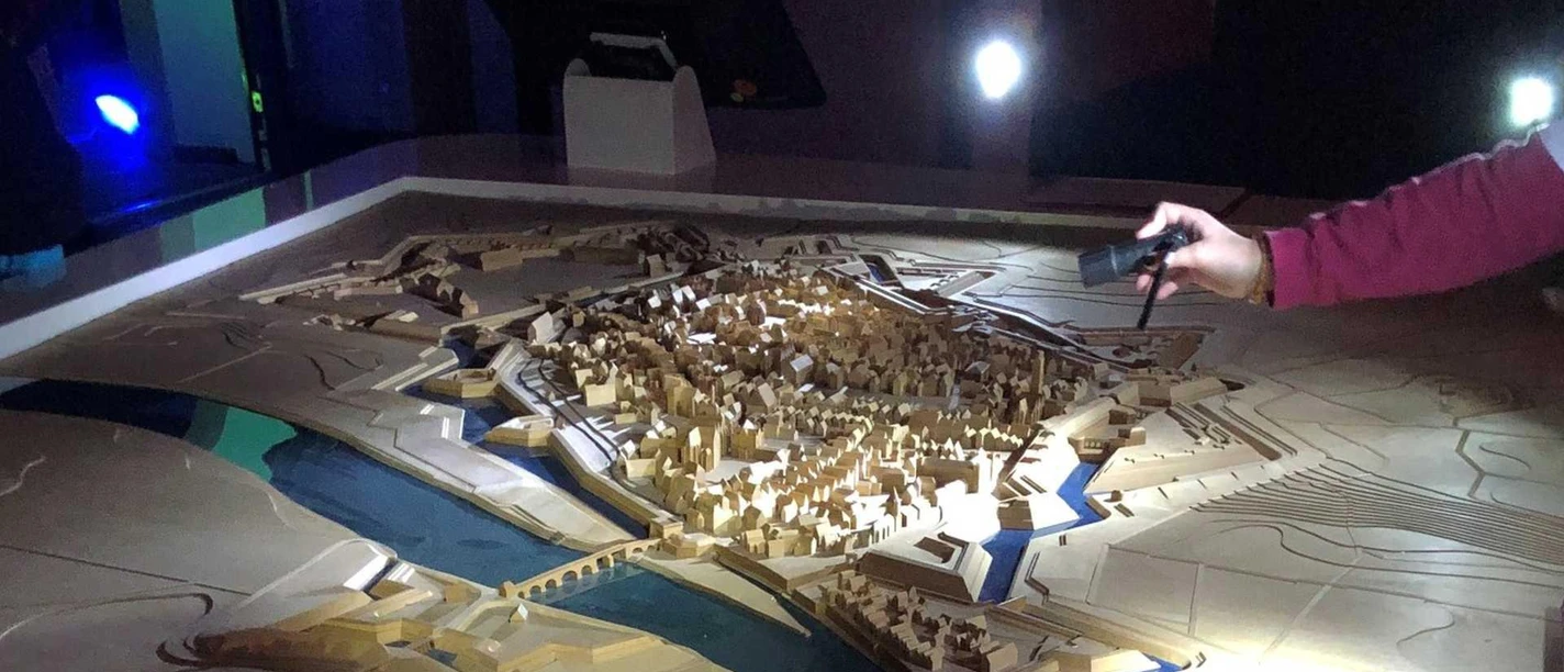 Taschenlampenfuehrung_Mindener_Museum Auf dem Bild ist ein Stadtmodell zu sehen, das sich im Dunkeln befindet und nur mit einer Taschenlampe angeleuchtet wird.