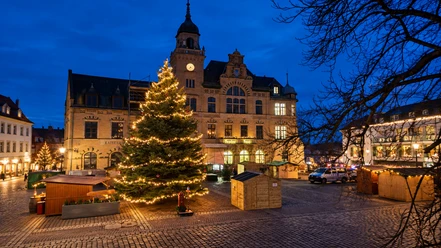 Festlicher Weihnachtsmarkt am historischen Rathausturm Der Weihnachtsmarkt in Bad Lausick ist vor dem historischen Rathaus aufgebaut mit beleutetem Weihnachtsbaum.
