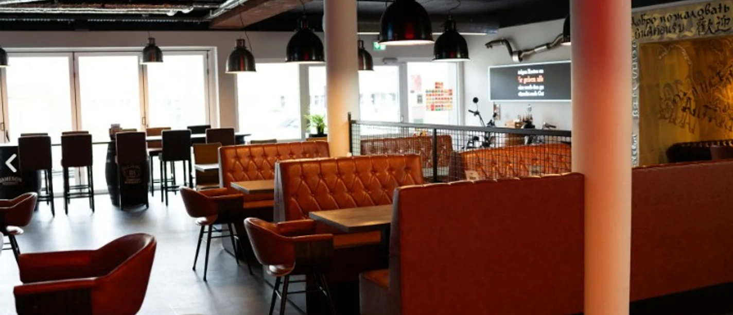 Kneipenquiz im City-Burger Modernes Restaurant mit orangefarbenen Lederbänken, Stühlen und schwarzen Hängelampen.