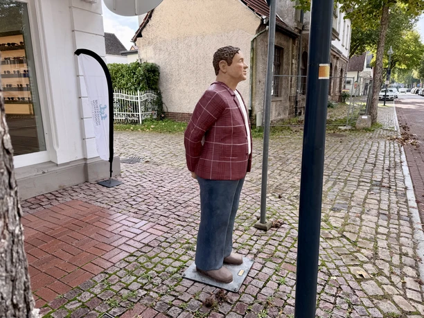 Herr Meyer (6).jpeg Lechner-Figur „Herr Meyer“ mit kariertem Hemd auf einem Gehweg in Petershagen.