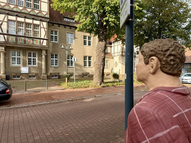 Herr Meyer (8).jpeg Lechner-Figur Herr Meyer blickt über die Straße zum historischen Fachwerkhaus.