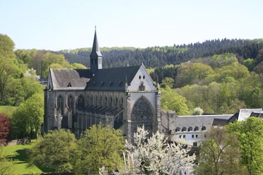 Altenberg Die Abtei von Altenberg, ein gotisches Bauwerk, umgeben von üppigem Grün und Waldlandschaft.
