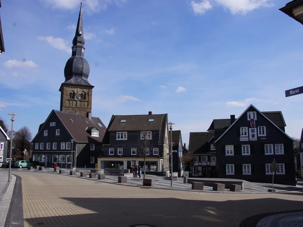 Marktplatz in Wermelskirchen Marktplatz mit historischer Fachwerkarchitektur und Kirchturm vor blauem Himmel in malerischer Kleinstadt.