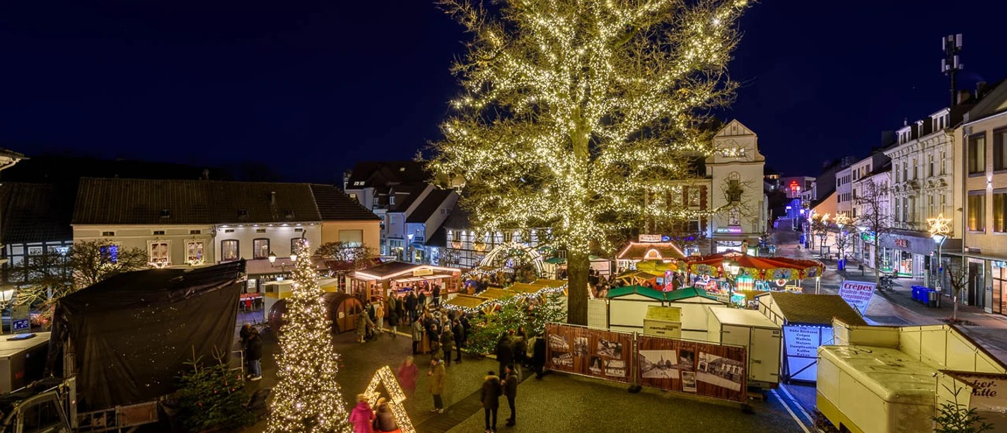 Hildener Martinsmarkt Festlich beleuchteter Platz bei Nacht mit strahlendem Lichterbaum und Marktständen.