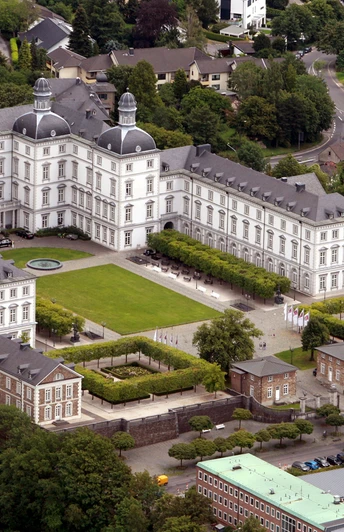 Blick auf Schloss Bensberg Luftaufnahme des barocken Schloss Bensberg in Bergisch Gladbach, umgeben von Grünflächen und Bäumen.