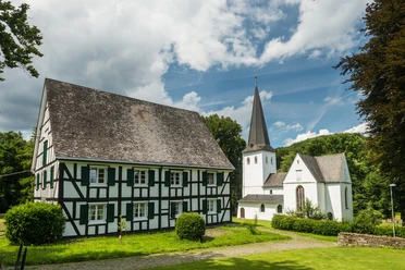 Bonte Kerke mit Fachwerkhaus <p>Fachwerkhaus und Kirche in ländlicher, grüner Umgebung unter blauem Himmel mit weißen Wolken.</p>
