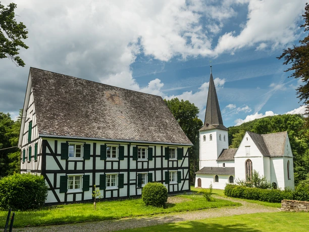 Bonte Kerke mit Fachwerkhaus <p>Fachwerkhaus und Kirche in ländlicher, grüner Umgebung unter blauem Himmel mit weißen Wolken.</p>