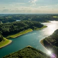 Große Dhünn- Talsperre Ein weitläufiger Stausee inmitten bewaldeter Hügel unter einem leicht bewölkten Himmel.