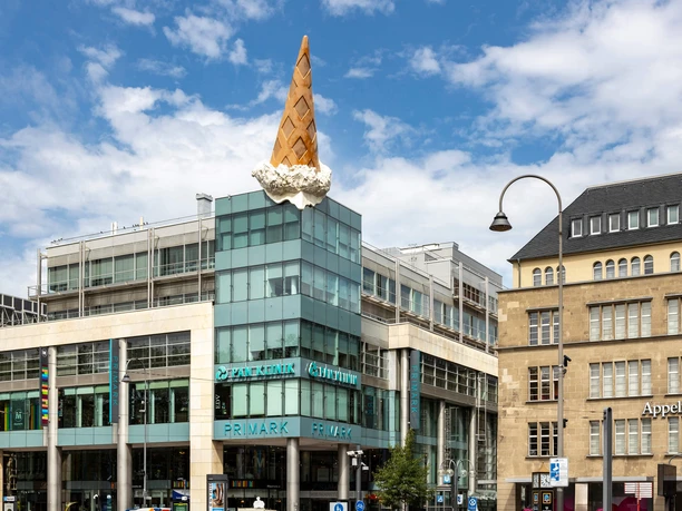 Dropped Cone Umgestürzte Eistüte auf einem Geschäftshaus in der Kölner Innenstadt unter blauem Himmel
