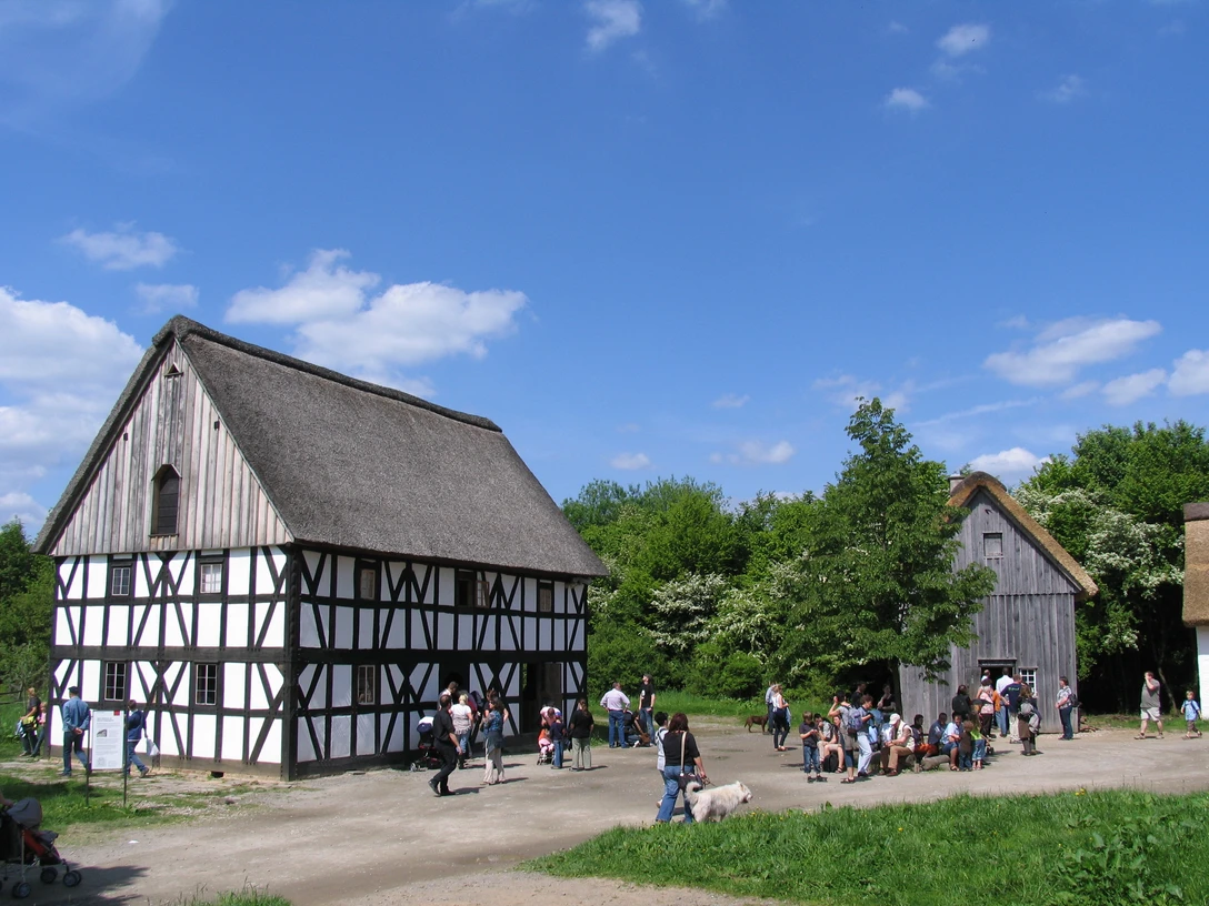 LVR-Freilichtmuseum Lindlar Zwei traditionelle Fachwerkhäuser mit Reetdächern und viele Besucher an einem sonnigen Tag im Freilichtmuseum.