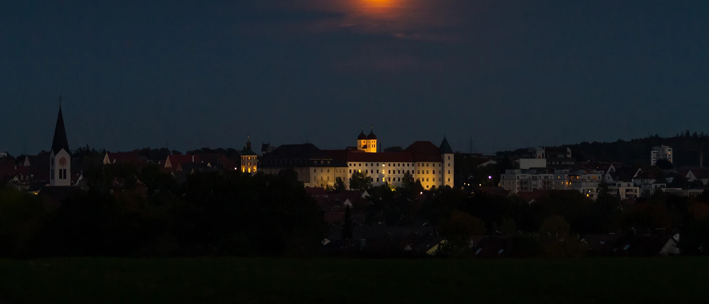 Mit der Taschenlampe durch die Zeit – abendliche Familientour Nächtliche Stadtansicht von Günzburg mit Vollmond, Kirchtürmen und beleuchtetem Schloss