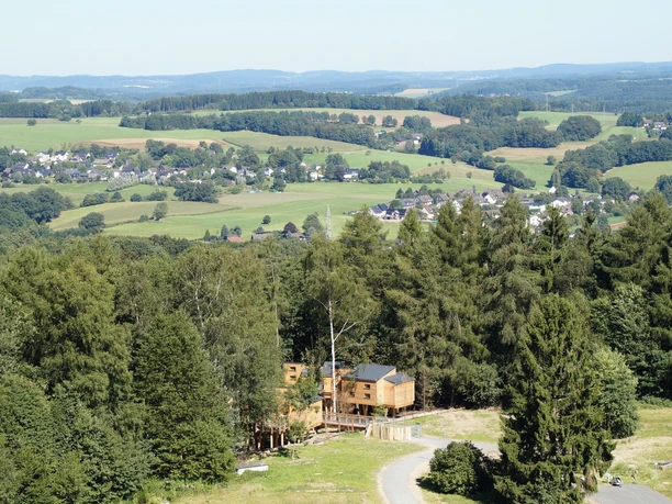 Ausblick vom Aussichtsturm auf Panarbora Blick auf eine bewaldete Hügellandschaft mit vereinzelten Häusern und Dörfern in der Ferne.