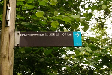 Wegweiser am Panoramasteig <p>Wegweiser zeigt Richtung Berg. Freilichtmuseum, Entfernung 0,1 km, umgeben von grünem Laub.</p>
