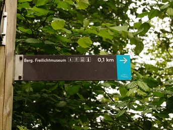 Wegweiser am Panoramasteig <p>Wegweiser zeigt Richtung Berg. Freilichtmuseum, Entfernung 0,1 km, umgeben von grünem Laub.</p>