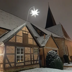 Adventsmarkt Blumläger Kirche - HBK Die Blumläger Kirche im Winter mit schneebedecktem Dach und einem leuchtenden Adventsstern als Dekoration.