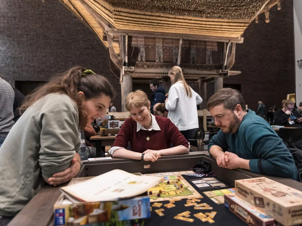 Boardgame Nacht im Museum Schnütgen Drei Menschen spielen Brettspiel im Museum Schnütgen vor historischer Architektur