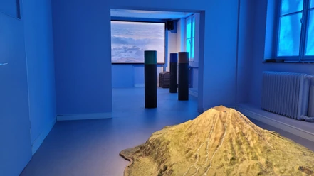 Remote Island Blau beleuchteter Ausstellungsraum mit Inselmodell, Säulen und Meeresprojektion