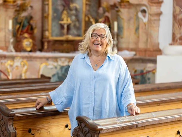 Ein Rokokojuwel - Kirchenführung durch die Frauenkirche Lächelnde Stadtführerin in der Frauenkirche Günzburg vor Rokokoaltar und Holzbänken
